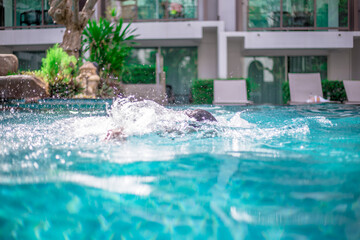 Waterfall blurred background That flows from the rocks, the garden decoration at the swimming pool is seen in the resort or hotel, allowing tourists to swim during the day.
