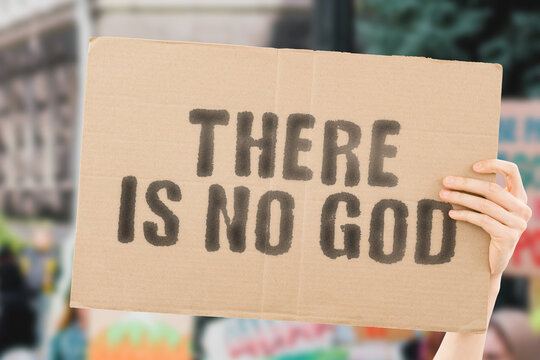 The phrase " There is no god " on a banner in men's hand with blurred background. Religion. Belief. Believe. Culture. Atheism. Disagree. Untruth. Refuse
