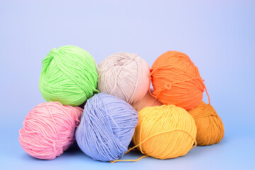 Piled multicolored wool for crocheting isolated on light blue background.