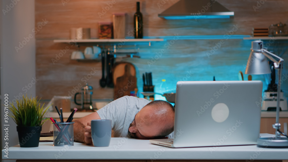 Poster overworked man sleeping on kitchen desk working remotely late hours at home. busy exhausted remote e