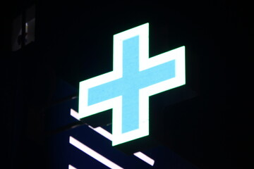 Glowing pixel cross of LED lamps on black background.