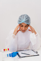 Tired female doctor in a protective clothing sits in the doctor's office.Medical and coronavirus...
