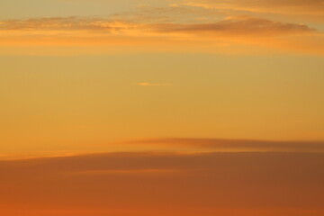 Fototapeta premium Sun below the horizon and clouds in the fiery dramatic orange sky at sunset or dawn backlit by the sun. Place for text and design
