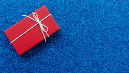 New Year's gift on a blue glitter background top view. Christmas background