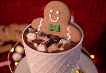 Delicious cup of hot chocolate with a gingerbread man cookie dipped in cinnamon sprinkled chocolates, ideal for a Christmas card.