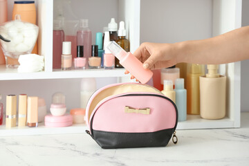 Bag, female hand and travel bottle with body care cosmetics in bathroom
