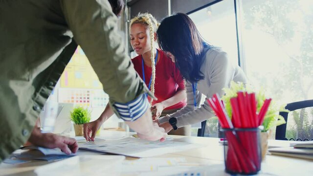 Group of creative designer and programing standing around table. Working process. Teamwork on new startups project. Coworkers discussing at table and working together on laptops and paper documents