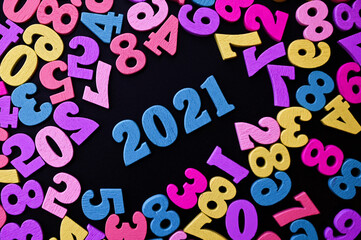 Happy New year 2021. Wooden numbers 2021 on black background surrounded with colorful numbers. New year concept. Flat lay. Close up of 2021