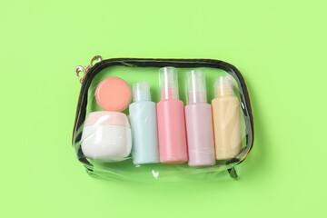 Transparent bag with travel  cosmetic products on color background