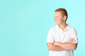 Smiling teenage boy with crossed arms on color background