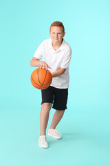 Sporty teenage boy playing basketball on color background