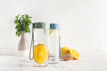 Bottles of infused water with citruses on light table