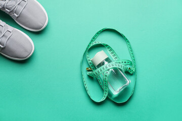 Bottle of water, sports shoes and measuring tape on color background