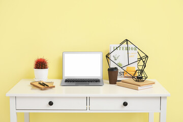 Stylish workplace with laptop near color wall