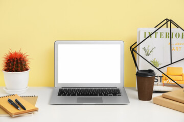 Stylish workplace with laptop near color wall