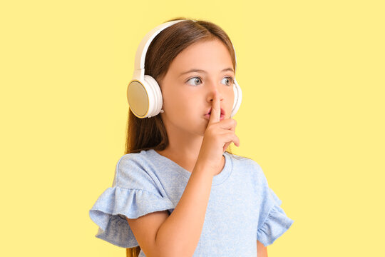 Cute little girl listing to music on color background
