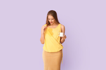 Stressed young woman with coffee stains on her t-shirt on color background