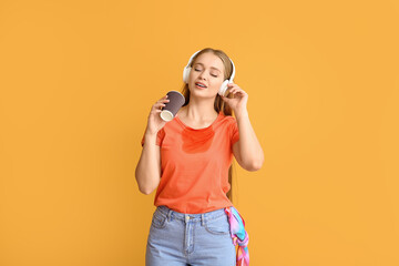 Young woman with coffee stains on her t-shirt and headphones on color background