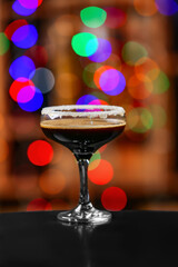 Glass of tasty espresso martini on blurred background