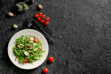 Plate with tasty arugula salad and ingredients on dark background