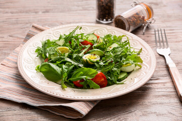 Plate with tasty arugula salad on wooden table
