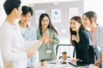 Asian businessman is opening champagne to celebrate the new year with the members of the business group