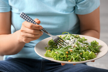 Woman eating tasty arugula salad, closeup