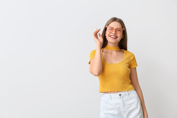 Happy woman with stylish sunglasses on light background