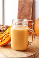 Mason jar of tasty pumpkin smoothie on table