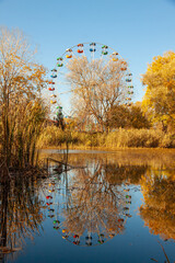 Ferris wheel with reflection in the blue water of the lake