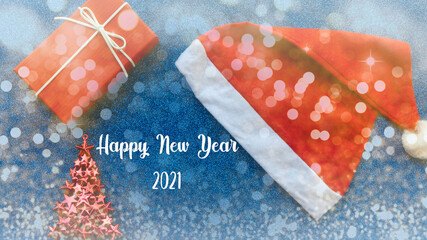 New Year concept. Santa Claus hat, gift, toy tree on a blue glitter background with the inscription.