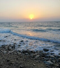 Rocks on sea waves and beautiful sunset