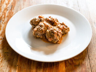 portion of meatballs with rice on white plate on old wooden table at home kitchen