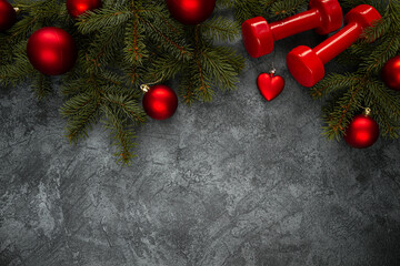 Two red dumbbells, Christmas tree branches with decorations, ornaments and baubles. Healthy fitness...