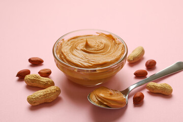 Peanut, bowl and spoon with peanut butter on pink background