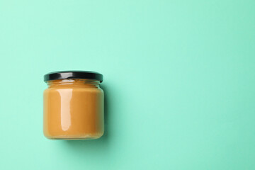 Blank jar with peanut butter on mint background
