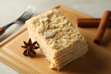 Wooden board with piece of Napoleon cake with cinnamon, close up