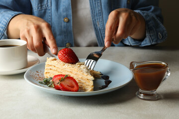 Woman eating delicious Napoleon cake, close up