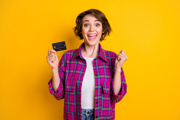 Photo of beautiful triumphant young lady hold plastic debit card win lottery money isolated on yellow color background