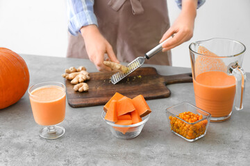 Woman preparing tasty pumpkin smoothie at table