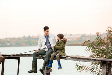 Little boy and his father fishing on river