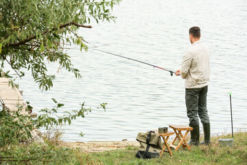 Obraz na płótnie Canvas Young man fishing on river