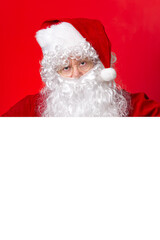 Santa Claus looking out from behind the blank white board isolated on red background with copy space