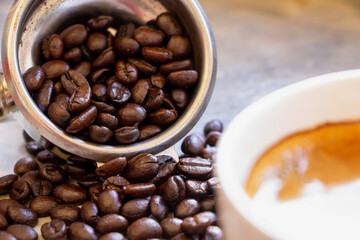 Fototapeta premium Close up of filter holder basket with organic dark brown roasted arabica coffee beans inside.