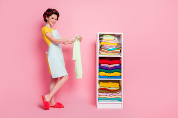 Full length body size view of nice cheerful housemaid organizing choosing things cleanup room...
