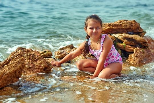 Little girl on vacation at a seaside resort . A child in a bathing suit takes a sun bath