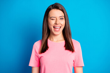 Photo portrait of funky female student winking blinking in pink clothes isolated on vibrant blue...