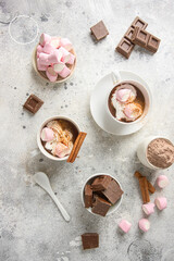 Top view of hot chocolate cups with whipped cream and marshmallow on concrete background....