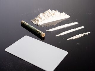 Lines of cocaine and a dollar bill. Cocaine lines shots on a black table glass. Cocaine powder,...