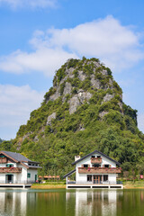 Fototapeta premium Outdoor waterside villas and blue sky, white clouds, green water and green mountains